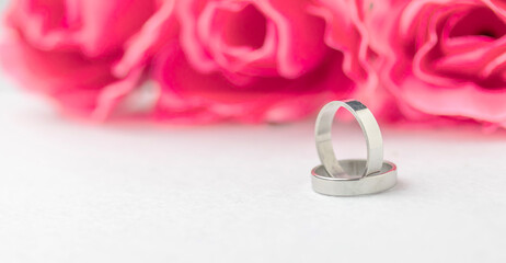 Wedding rings lie near a beautiful bouquet as bridal accessories.Wedding rings and roses bouquet.concept for a wedding card.