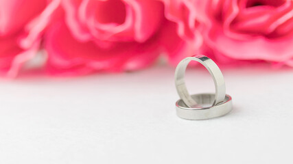 Wedding rings lie near a beautiful bouquet as bridal accessories.Wedding rings and roses bouquet.concept for a wedding card.