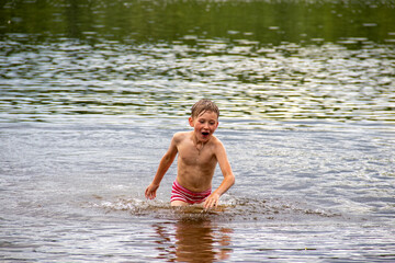 boy runs along the river. emotions. joy. holidays. relaxation. relax. bright photo. child. kid. sea. swimming trunks. summer. warm.