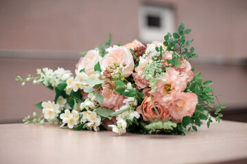 Orange and green wedding bouquet on the beige table