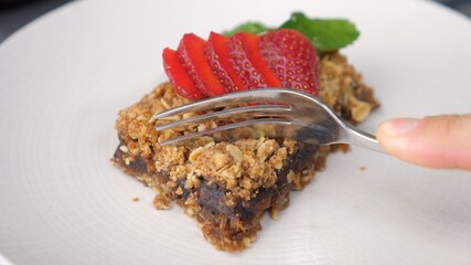 Fork breaking vegan pie decorated with strawberries. Healthy organic vegan desserts. 
