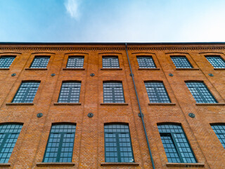 Fototapeta na wymiar Upward view to high red brick building with a lot of windows