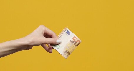 Female hands holding euro banknotes on a yellow background. Euro Money in woman hand. Euro cash...