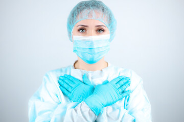 a nurse in a medical gown, mask, and protective gloves pressed her hands to her chest