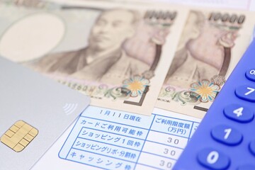 クレジットカードの利用可能額に関する書類とお金、電卓
