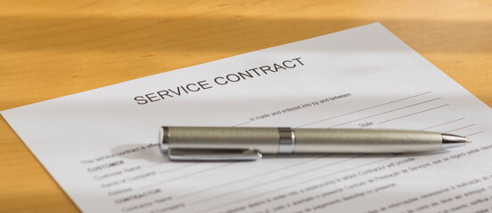 A service contract on the table.
A agreement form on the desk
A contract form and pen  on the table.
A document on the desk