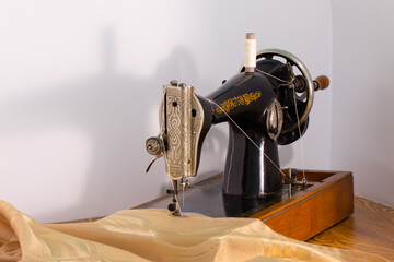 gray sewing machine on a white background with golden fabric