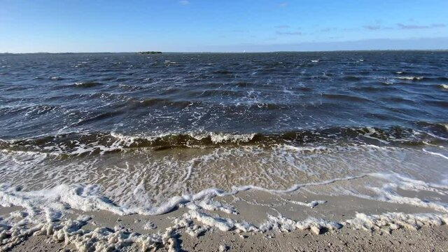 The waves along the seashore slowly rolling in over the sand.