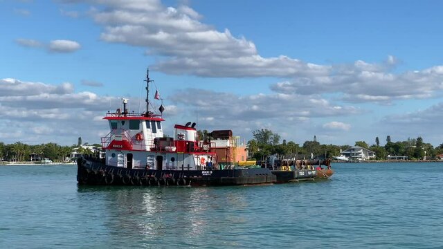 Sarasota, Florida - December 19, 2020: A tugboat sitting in the clear blue water of an inlet from the Gulf of Mexico.