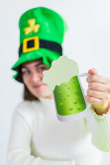 Cheerful young woman celebrating St. Patrick 's Day. Hand holding beer glass silhouette..
