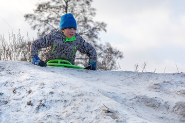Fototapeta na wymiar happy boy descends from a snowy mountain, horizontal.