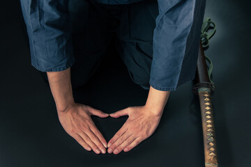刀を脇に置いて礼をする人物