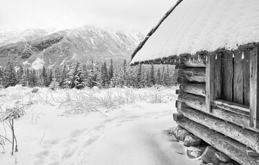 Black and white picture of wooden hut at Gasienicowa Valley (Hala Gasienicowa) during snowy winter, Tatra Mountains, Poland.