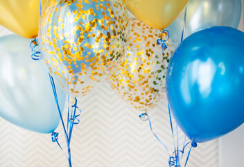 Blue and transparent balloons with golden confetti on zigzag wallpaper background