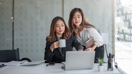 Two asian businesswoman working laptop computer working and coffee at the office.