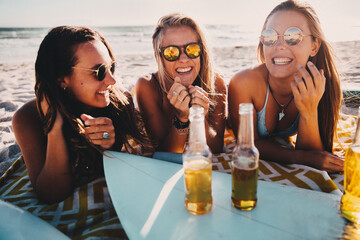 Happy group of female friends drinking beer at the beach and having fun on vacation