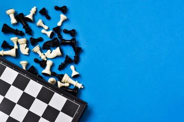 Chess board and chess figures on blue background. Flat lay, copy space. Black and white chess...