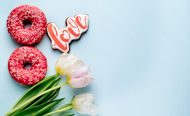 Fototapeta na wymiar International Women's Day. 8 march number eight consisting of donuts next to tulips and heart-shaped cookies on a light blue background with copy space for your text
