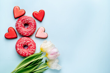 International Women's Day. 8 march number eight consisting of donuts next to tulips and heart-shaped cookies on a light blue background with copy space for your text