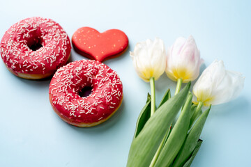 International Women's Day. 8 march number eight consisting of donuts next to tulips and heart-shaped cookies on a light blue background with copy space for your text