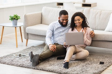 Black couple having videocall using laptop waving hands