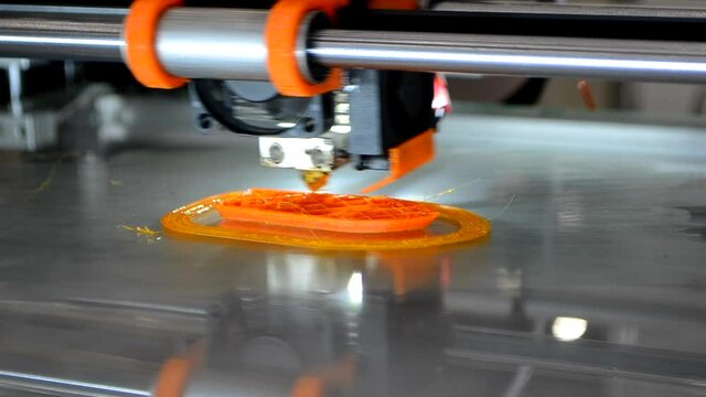 3d printer prints orange object model orange color close-up.