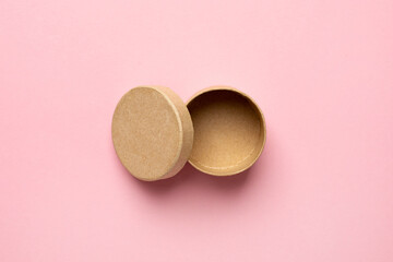 Small round decorative wooden box with opened lid on a pink background
