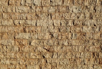 Exterior wall made of rough brown granite bricks. Background and texture 