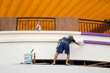 Hombre pintando la fachada de una casa.