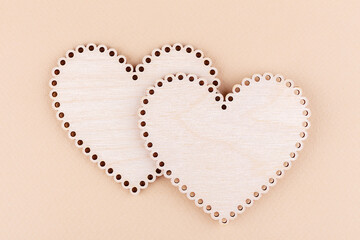 Two wooden hearts overlap on a neutral beige background. Close-up, copy space, top view. Minimal concept.