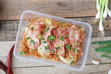 stilr fried instant noodle with pork on the table, fast food Asain style in plastic box
