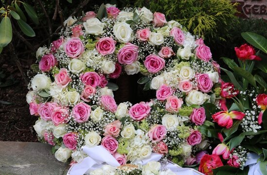 Ein runder Trauerkranz mit Rosen schm&uuml;ckt ein Grab nach Beerdigung