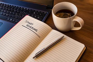 Notebook with agenda and cup of tea next to it. Smartworking and telecommuting.