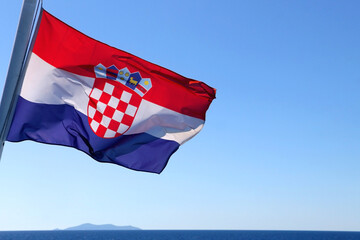 Flag of Croatia, blowing in the wind. Adriatic sea and bright sky in the background. Selective...