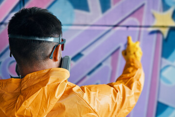 Street artist painting colorful graffiti on wall