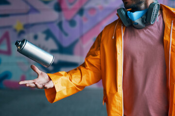 Graffiti artist throw his spray paint can against colorful graffiti