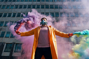 Young man in respirator mask hold smoke bombs in raised hands