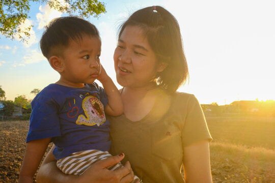 Mother hold little boy in park sunset light