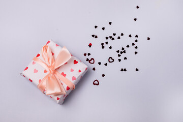 Gift Box with Bow on Light Blue Background Red Confetti Top View Horizontal Holiday Concept or Background Valentine Day