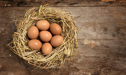Top view fresh eggs on nest on old wooden background.