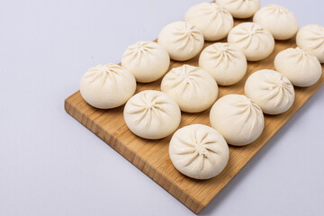 Fototapeta premium Raw and Frozen Homemade Pelmeni on Wooden Tray on Blue Background Horizontal Russian Cuisine