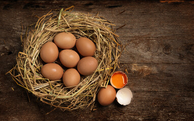 Top view fresh eggs on nest on old wooden background.