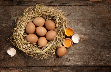 Top view fresh eggs on nest on old wooden background.
