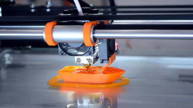 3d printer prints orange object model orange color close-up.