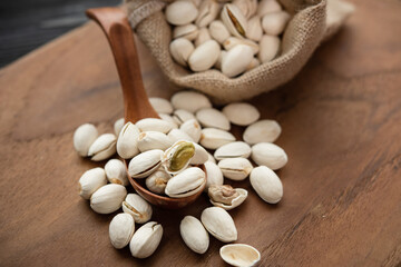 Pistachios in a wooden spoon. Sack with pistachios on a wooden table. (selective focus; close-up shot)