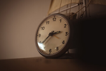 Low angle shot of vintage clock on wooden table against white wall. Concept of passing time.