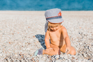 Toddler girl playing with pebbles on beach
