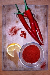 Chili red spicy peppers lemon slices, ground paprika on wooden cutting board vegetable ingredients decoration 