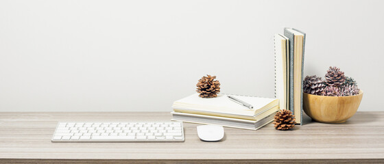 Workspace with book, keyboard and mouse on wood table with living room white wall. Panoramic banner of workplace with copy space