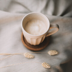 Fototapeta na wymiar Cup of coffee with milk on beige plaid. Flat lay, top view still life morning breakfast. Comfort, cosiness and warmth concept. Photo in light pastel colors